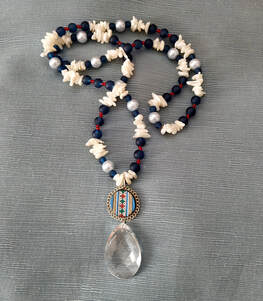 Long necklace of blue white and red beads with colourful medallion and large crystal pendant